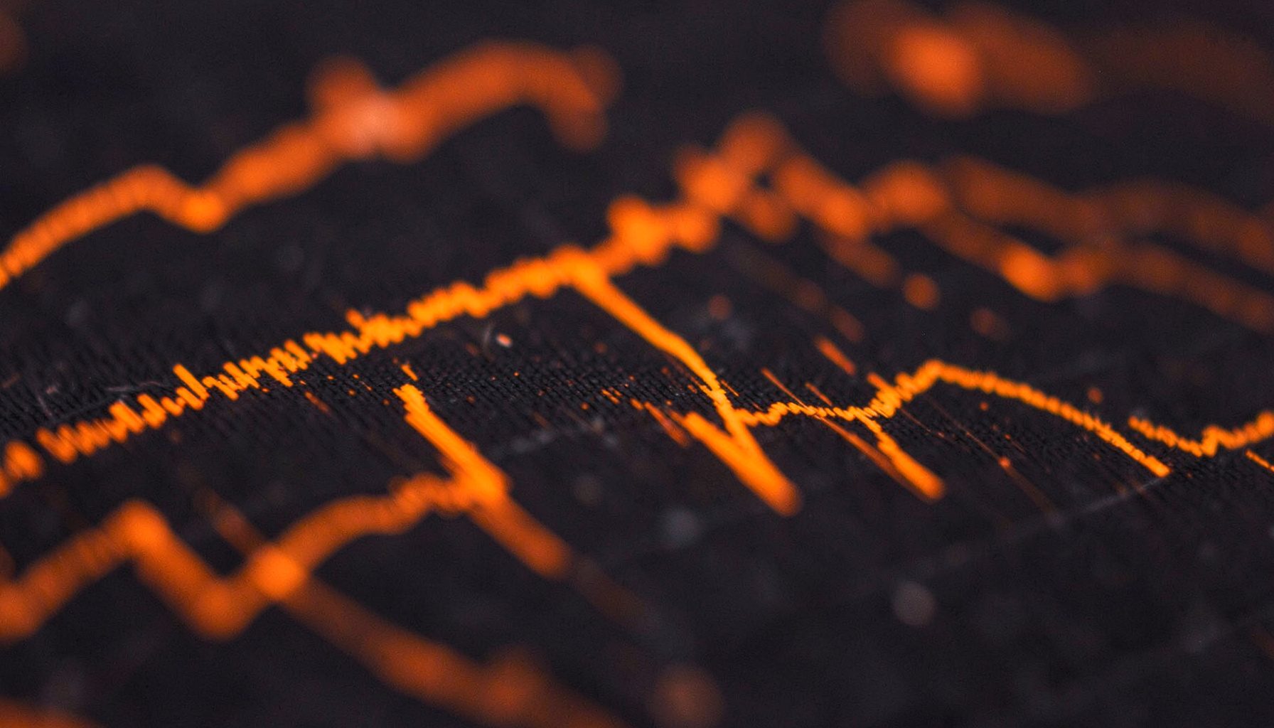 Close-up of audio editing waveforms on a dark screen with orange highlights, technical and focused