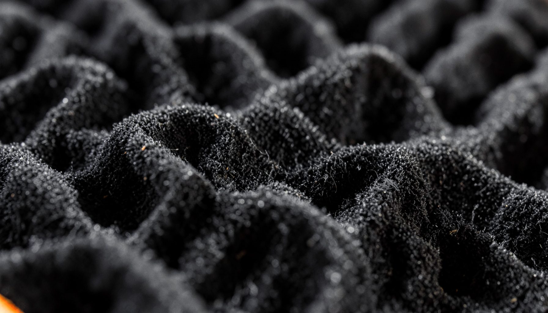 Close-up of acoustic foam panel texture in deep charcoal and slate gray, soft directional light revealing subtle peaks