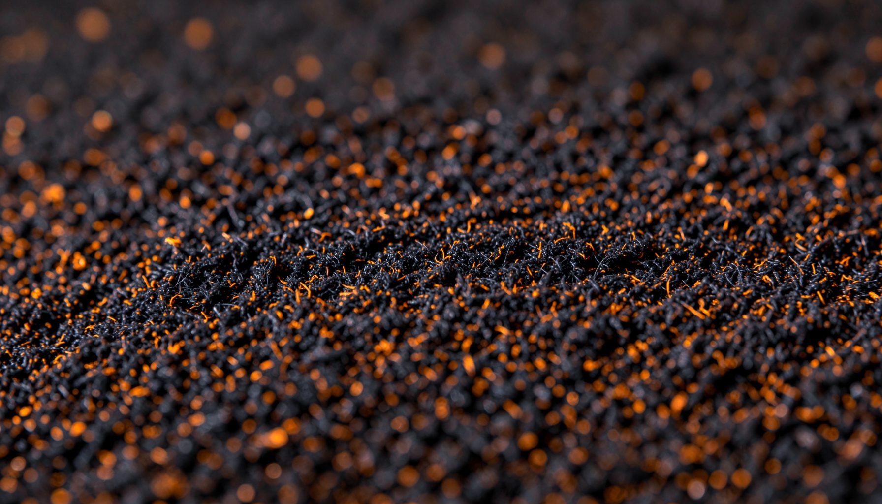 Extreme close-up of dark acoustic foam texture with deep charcoal and warm amber highlights, soft diffused lighting across the surface